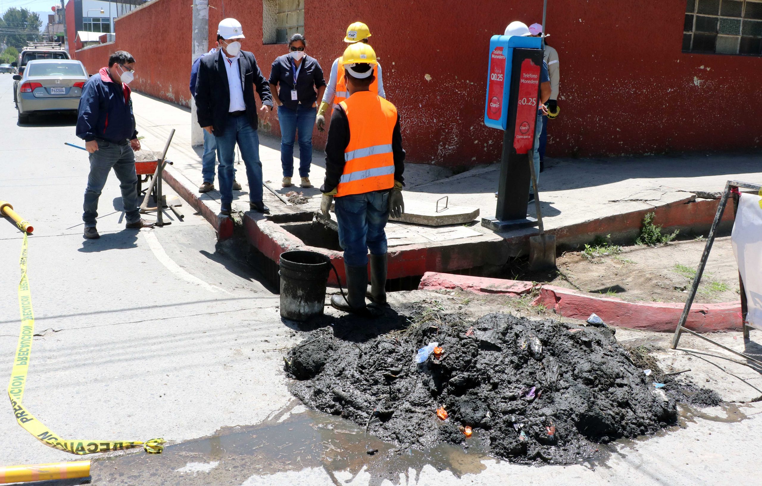 Una cantidad de lodo y basura es sacada en un tragante en la zona 3 de Quetzaltenango, el cual es observado por el alcalde Juan Fernando López, de casco blanco. (Foto: Carlos Ventura)